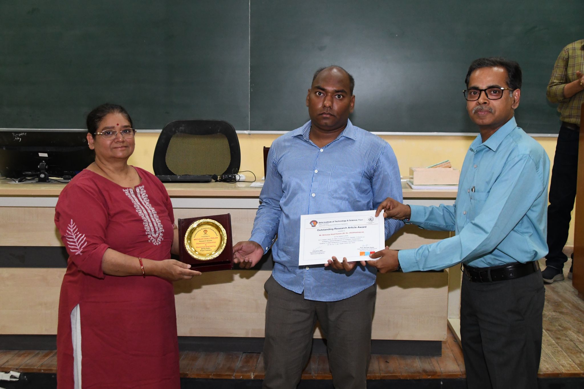 Receiving the Outstanding Research Article Award certificate and shield
