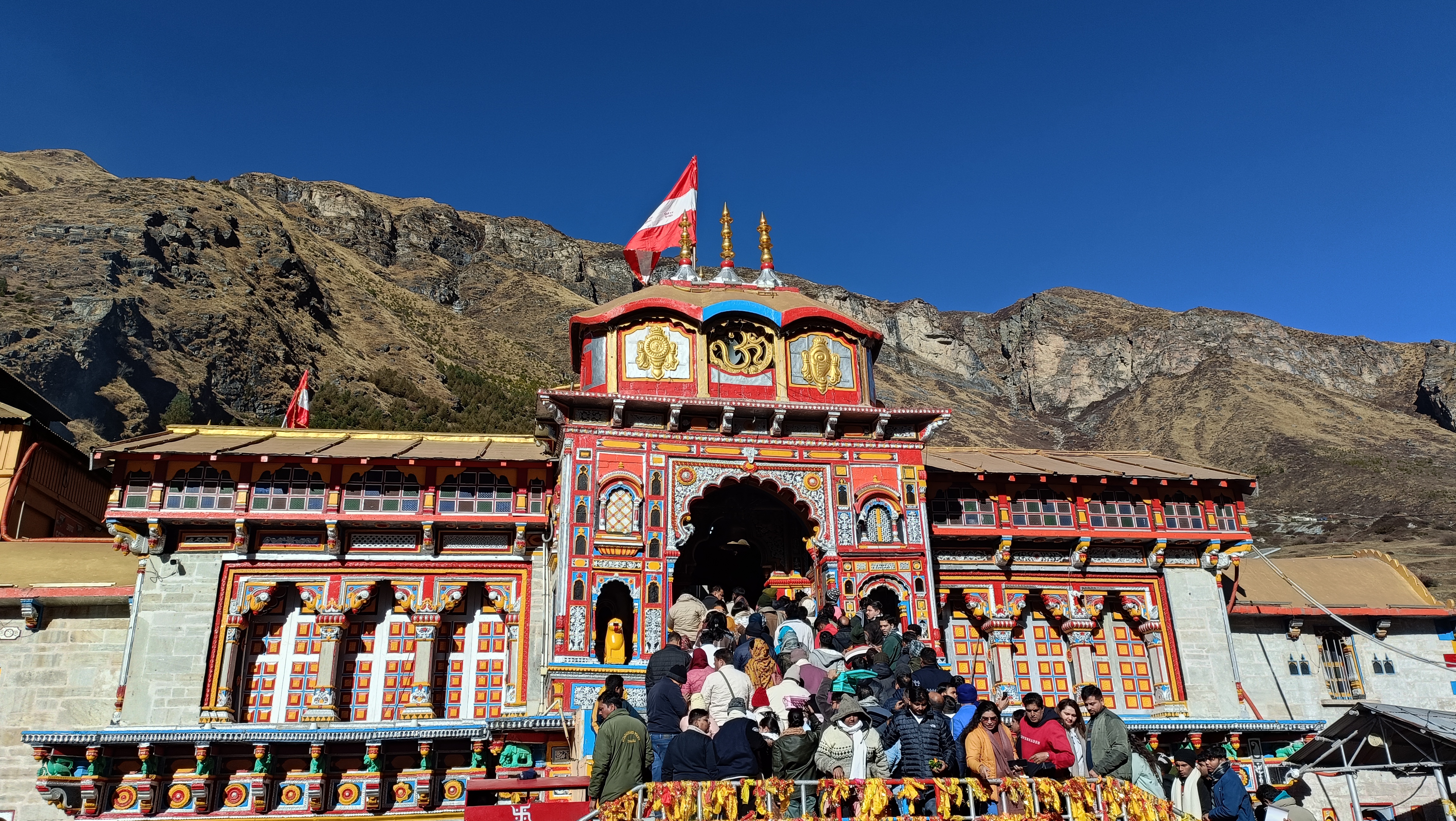 सामने से बद्रीनाथ मंदिर, नीला आकाश और पहाड़