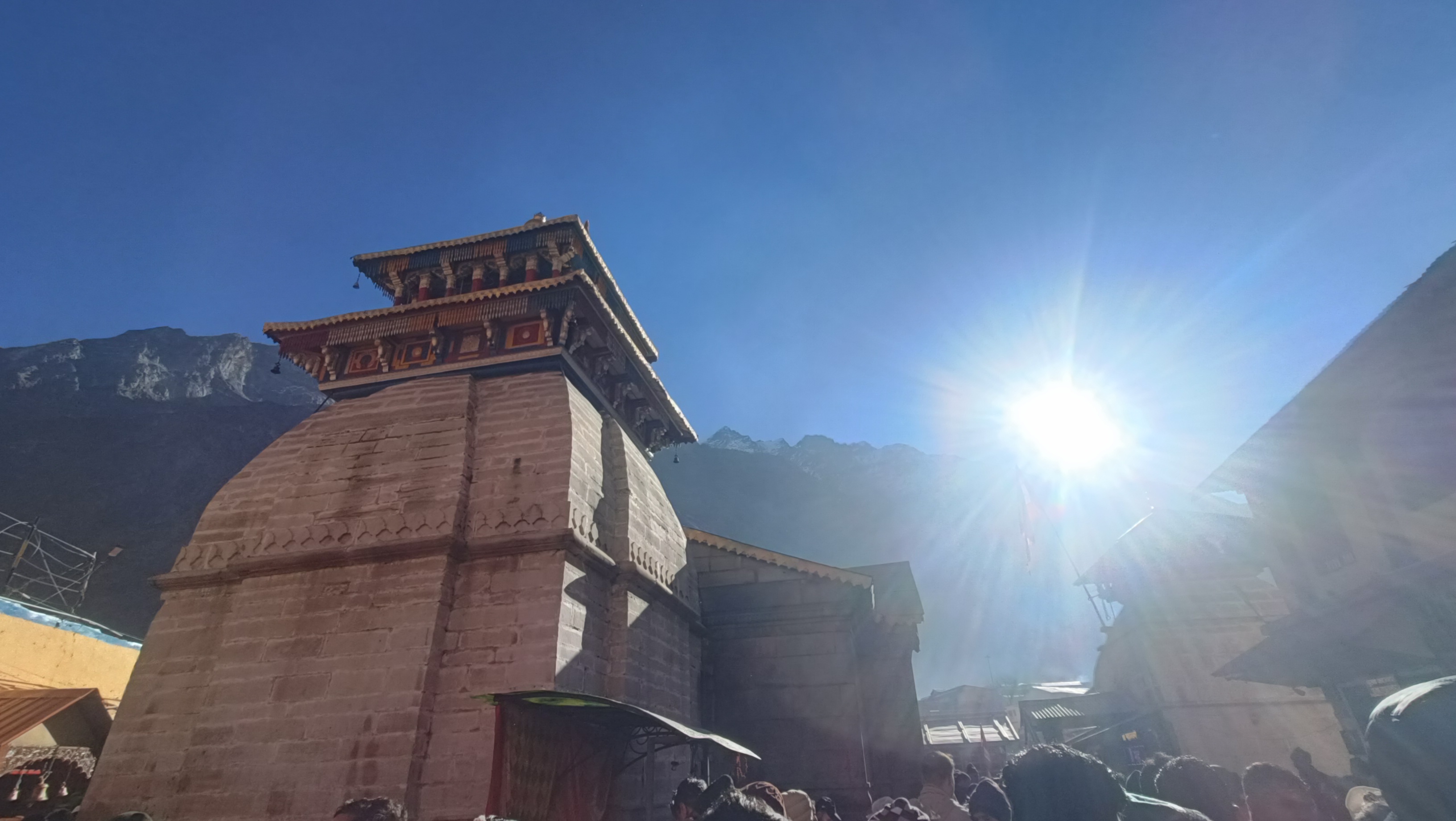 बद्रीनाथ मंदिर परिसर में सूर्य प्रकाश और श्रद्धालुओं की भीड़